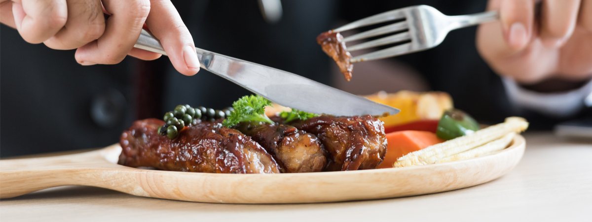 persona che mangia un piatto di carne